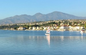A serene waterfront scene with calm blue water reflecting the sky. 