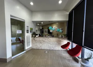 The image shows the interior of a modern, clean, and welcoming space, likely a dental office or medical facility.