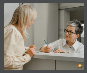 A front desk person with a set of forms and pencil in her hand while talking to a patient.